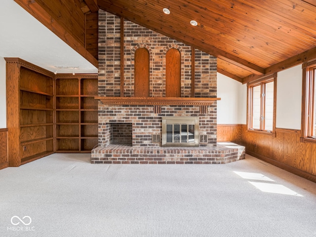 unfurnished living room featuring a wainscoted wall, wood walls, wood ceiling, vaulted ceiling, and a fireplace