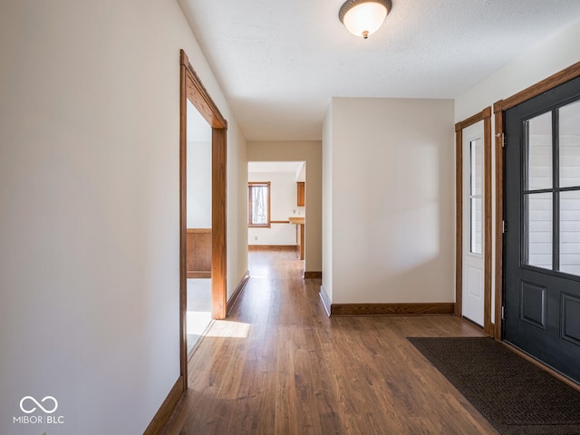 foyer entrance with wood finished floors, baseboards, and a textured ceiling