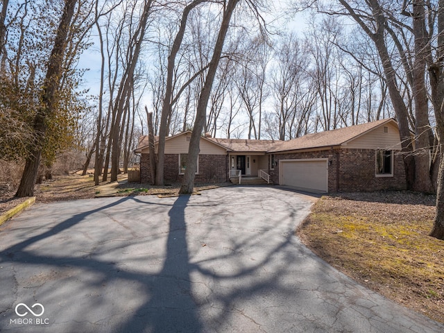 ranch-style house with aphalt driveway, brick siding, and an attached garage