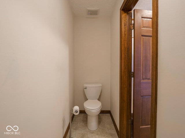 bathroom featuring visible vents, toilet, a textured ceiling, tile patterned flooring, and baseboards