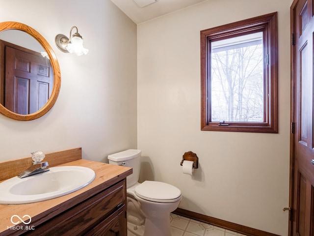 half bathroom featuring vanity, toilet, and baseboards