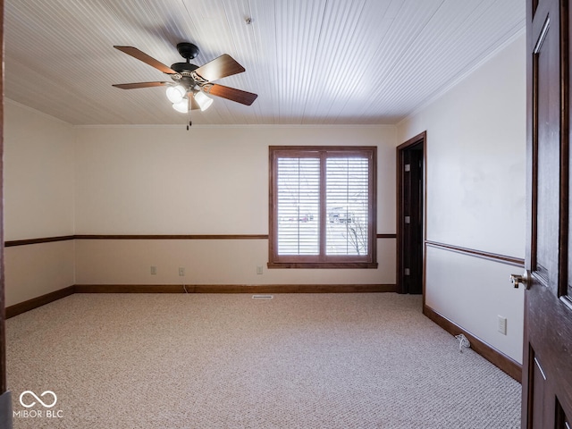 carpeted spare room with baseboards, ceiling fan, and ornamental molding