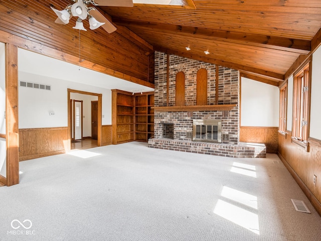 unfurnished living room featuring a wainscoted wall, wood walls, and visible vents