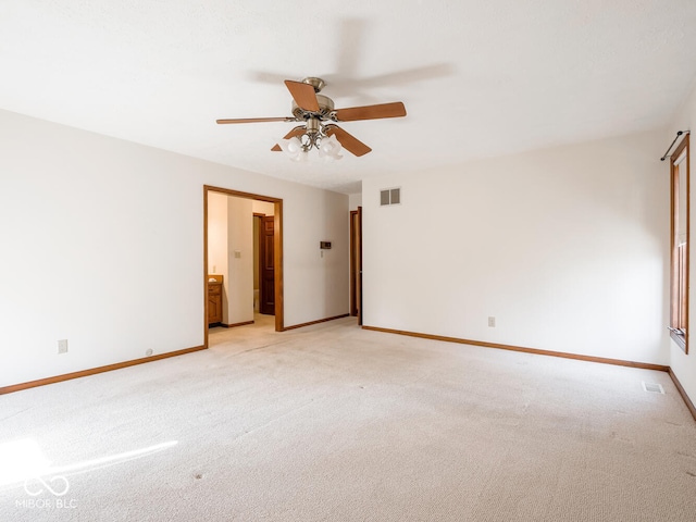 unfurnished bedroom featuring visible vents, ensuite bathroom, baseboards, light colored carpet, and ceiling fan