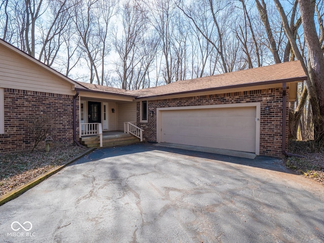 ranch-style home with a garage, brick siding, covered porch, and driveway