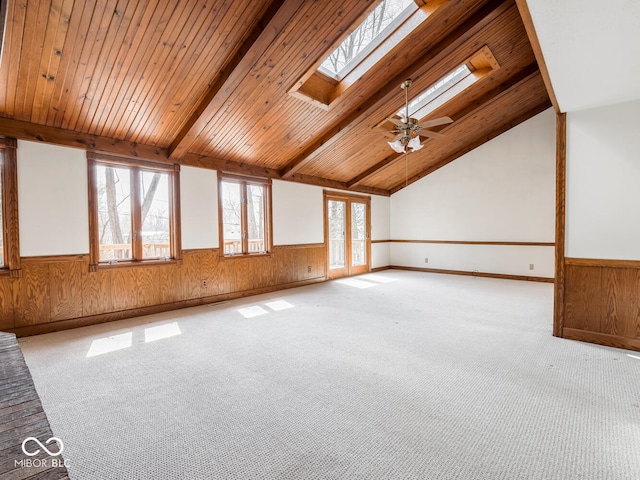 interior space featuring vaulted ceiling with skylight, wooden walls, and a wainscoted wall