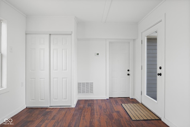 foyer entrance with ornamental molding, dark wood-style floors, visible vents, and baseboards