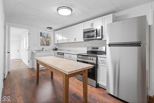 kitchen featuring dark wood-style floors, a sink, stainless steel appliances, light countertops, and white cabinets