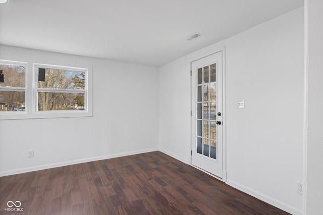 unfurnished room with visible vents, dark wood-type flooring, and baseboards