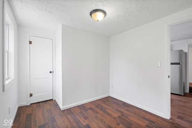 spare room featuring dark wood finished floors, baseboards, and a textured ceiling