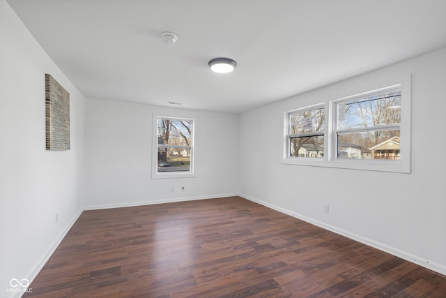 spare room with baseboards and wood finished floors