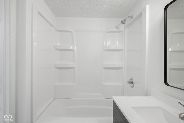 full bath featuring vanity, a shower, and a textured ceiling