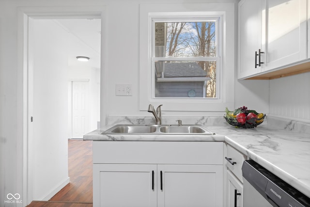 kitchen with dark wood-type flooring, a sink, stainless steel dishwasher, white cabinetry, and light countertops