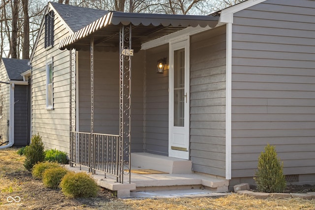 view of exterior entry with roof with shingles