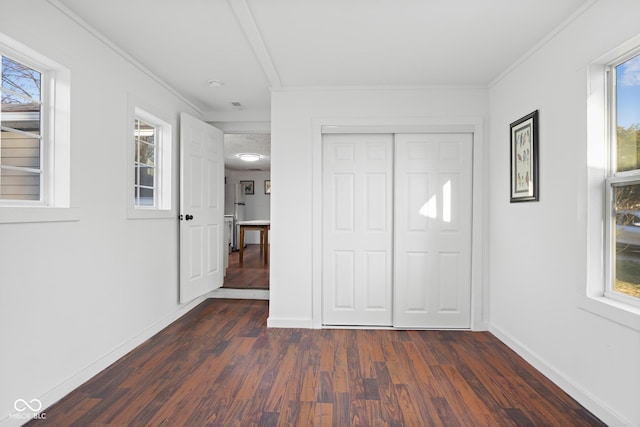 unfurnished bedroom featuring a closet, baseboards, ornamental molding, and dark wood-style flooring