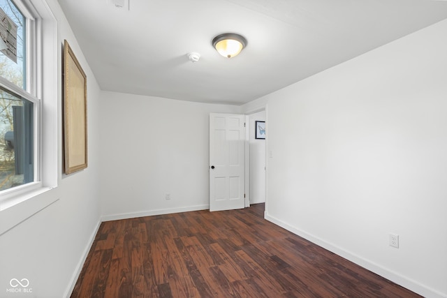 empty room featuring dark wood-style floors and baseboards