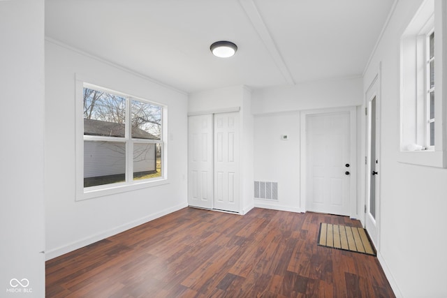 empty room with dark wood finished floors, baseboards, and visible vents