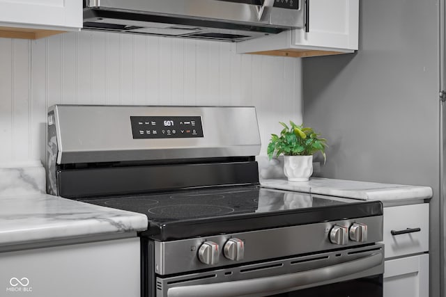 details with light stone counters, white cabinetry, and stainless steel range with electric cooktop