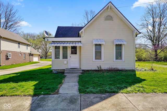 bungalow-style home with a shingled roof, a detached garage, and a front lawn