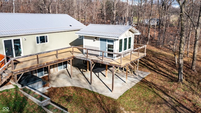 back of property with metal roof, a deck, and a patio area