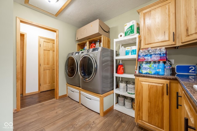 laundry area featuring baseboards, light wood-type flooring, washer and dryer, cabinet space, and a textured ceiling