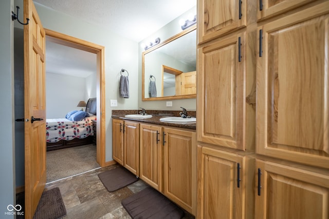 full bathroom featuring double vanity, stone finish flooring, ensuite bathroom, and a sink