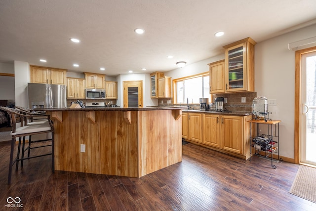 kitchen featuring a kitchen bar, dark wood finished floors, and stainless steel appliances