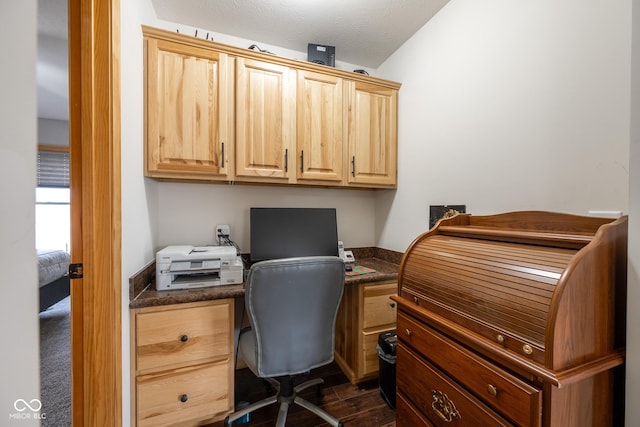 home office with a textured ceiling, dark wood finished floors, and built in desk