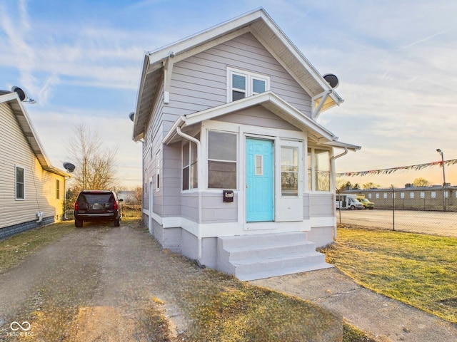 view of front of house featuring entry steps, driveway, and fence