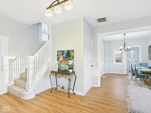 stairway with visible vents, baseboards, an inviting chandelier, and wood finished floors