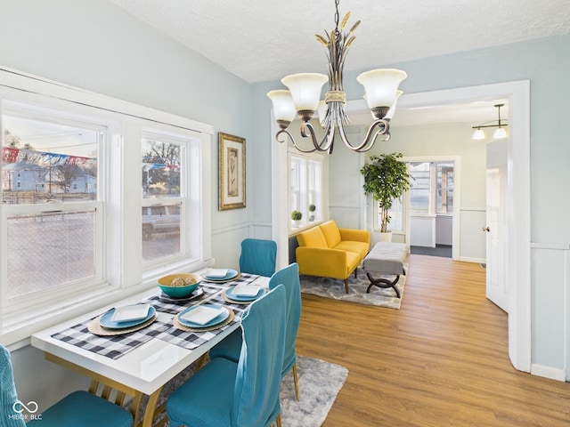 dining room with light wood-style floors, an inviting chandelier, and a textured ceiling