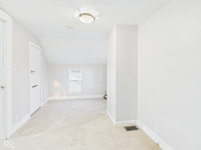 hallway featuring visible vents, carpet floors, baseboards, and vaulted ceiling