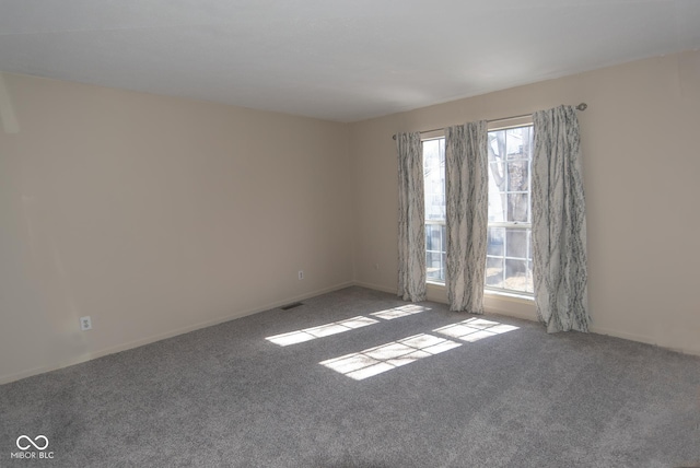 carpeted empty room featuring visible vents