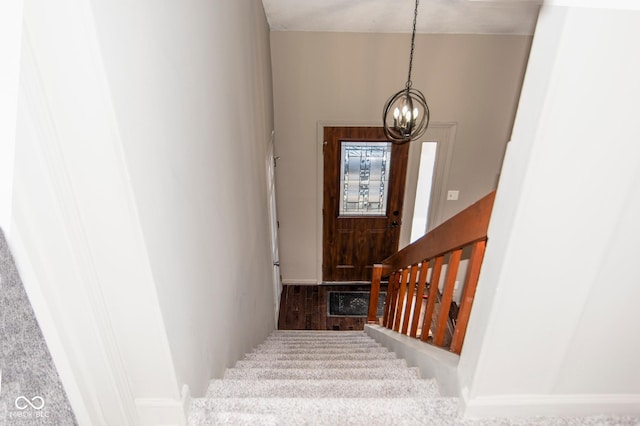 staircase with wood finished floors, baseboards, and a chandelier