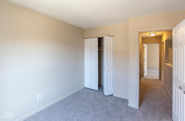 unfurnished bedroom with a closet, a textured ceiling, baseboards, and carpet floors