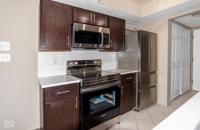 kitchen with a textured ceiling, appliances with stainless steel finishes, light countertops, light tile patterned floors, and decorative backsplash