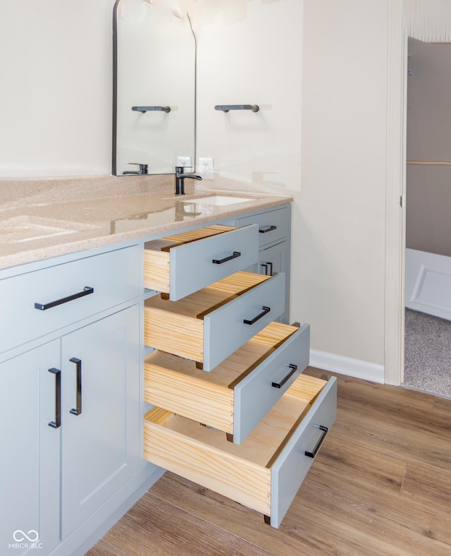 bathroom with a sink, baseboards, and wood finished floors