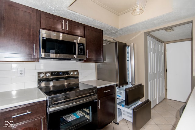 kitchen with light countertops, light tile patterned floors, tasteful backsplash, and appliances with stainless steel finishes