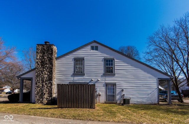 back of property with central air condition unit, a yard, and a chimney