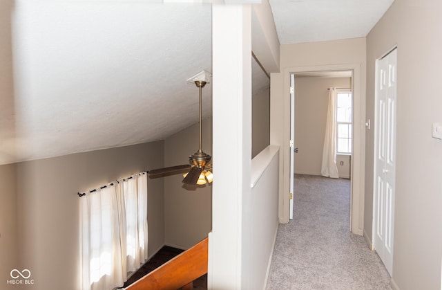 hall with lofted ceiling, carpet, and a textured ceiling