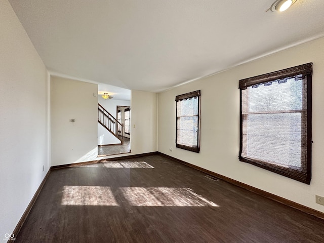 spare room featuring visible vents, stairs, baseboards, and wood finished floors