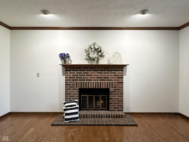 unfurnished living room with wood finished floors, baseboards, a fireplace, a textured ceiling, and crown molding