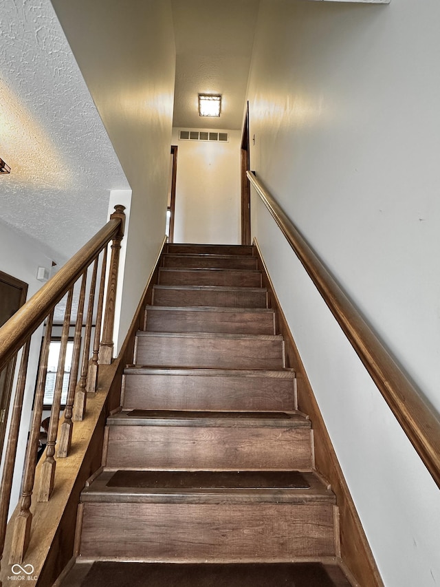 stairs with visible vents and a textured ceiling