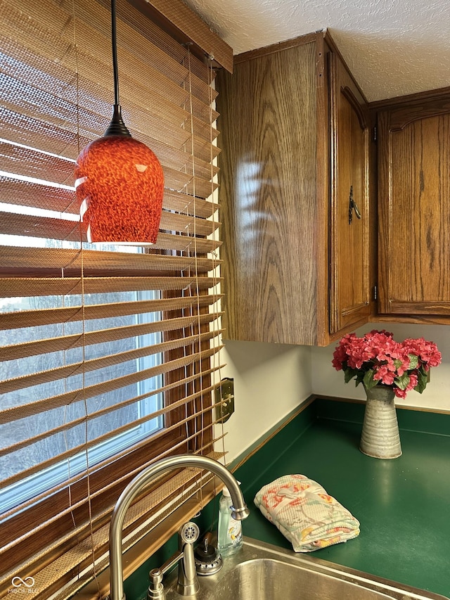 interior details with brown cabinets, a textured ceiling, and a sink