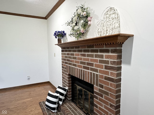 room details featuring a textured ceiling, wood finished floors, a fireplace, crown molding, and baseboards