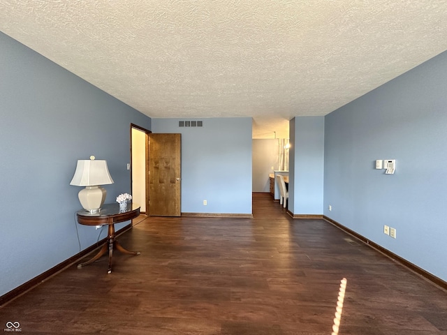 interior space featuring a textured ceiling, wood finished floors, visible vents, and baseboards