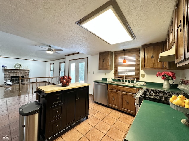 kitchen with light tile patterned floors, ceiling fan, a sink, under cabinet range hood, and appliances with stainless steel finishes