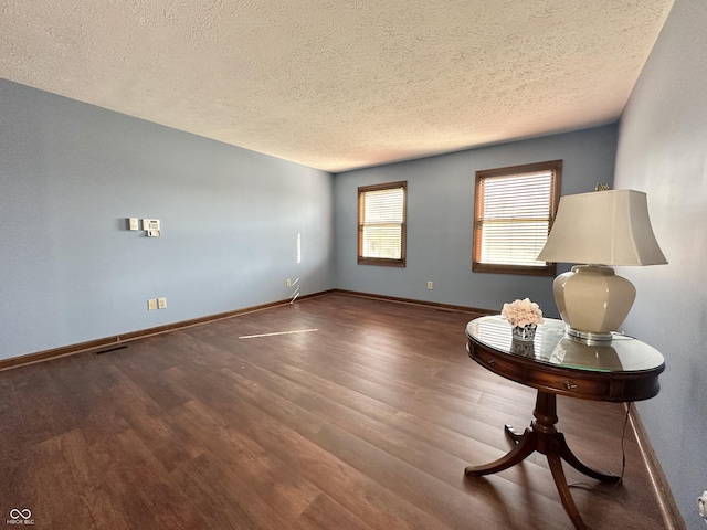 unfurnished room with wood finished floors, baseboards, and a textured ceiling