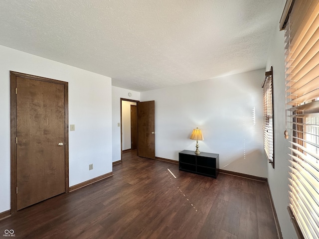 unfurnished bedroom with a textured ceiling, baseboards, and wood finished floors