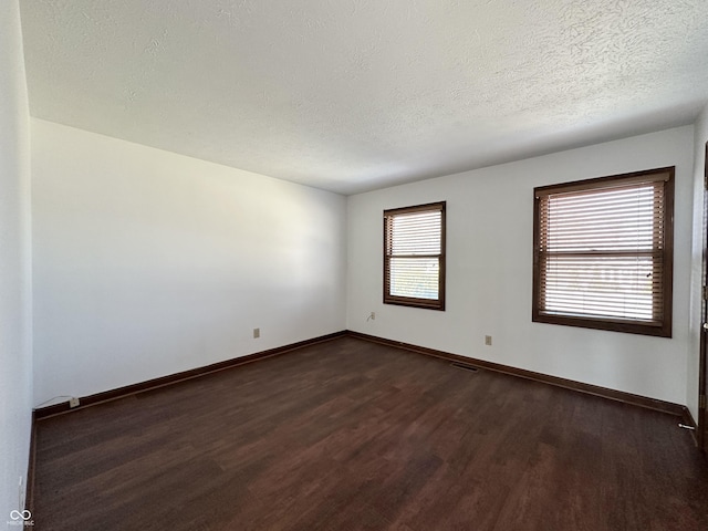 unfurnished room featuring dark wood finished floors, a textured ceiling, and baseboards